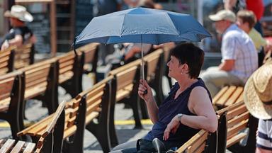 Wernigerode: Mit einem Schirm sitzt eine Frau in Wernigerode auf einer Bank.