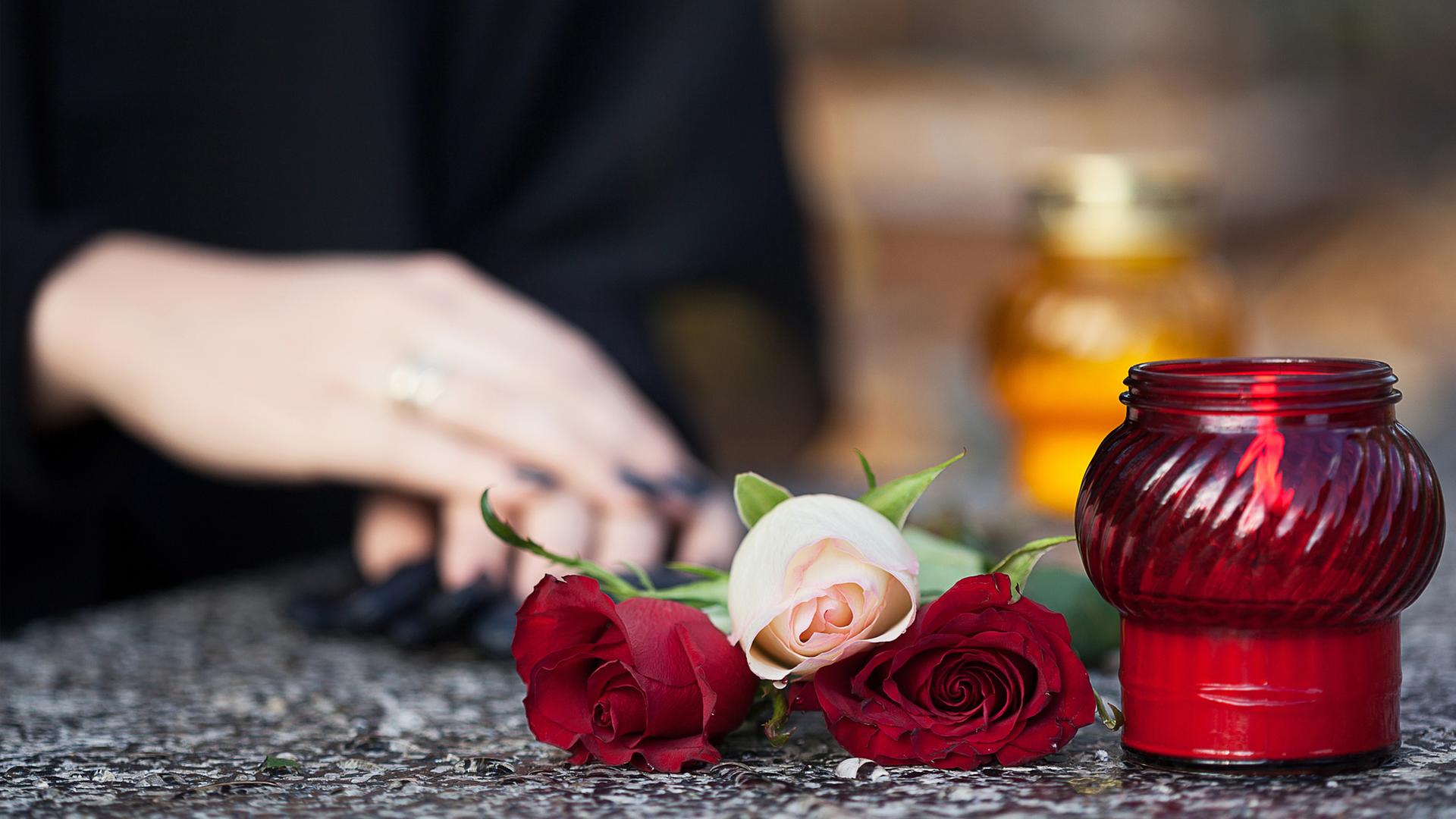 Symbolbild: Eine Frau trauert an einem Grab