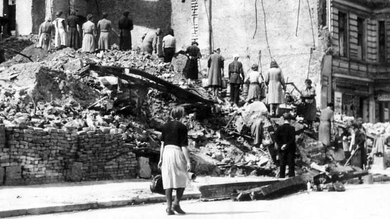 Frauen arbeiten an vom Krieg zertörten Häusern