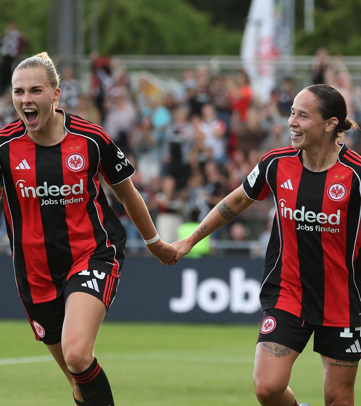 Fußballerinnen Laura Freigang und Géraldine Reuteler von Eintracht Frankfurt halten sich bei dem Spiel gegen SGS Essen am 05.09.2025 gemeinsam an der Hand.
