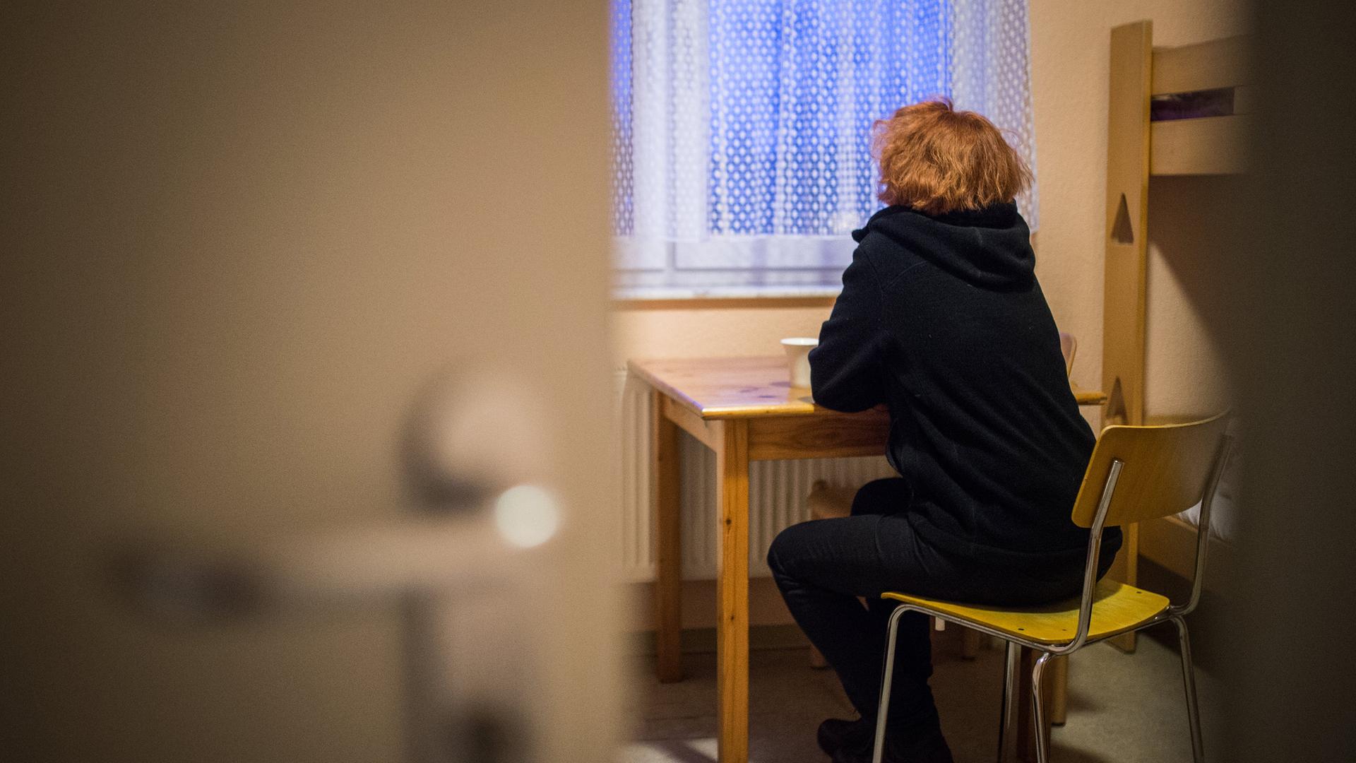 Eine Frau blickt in einem Frauenhaus aus dem Fenster