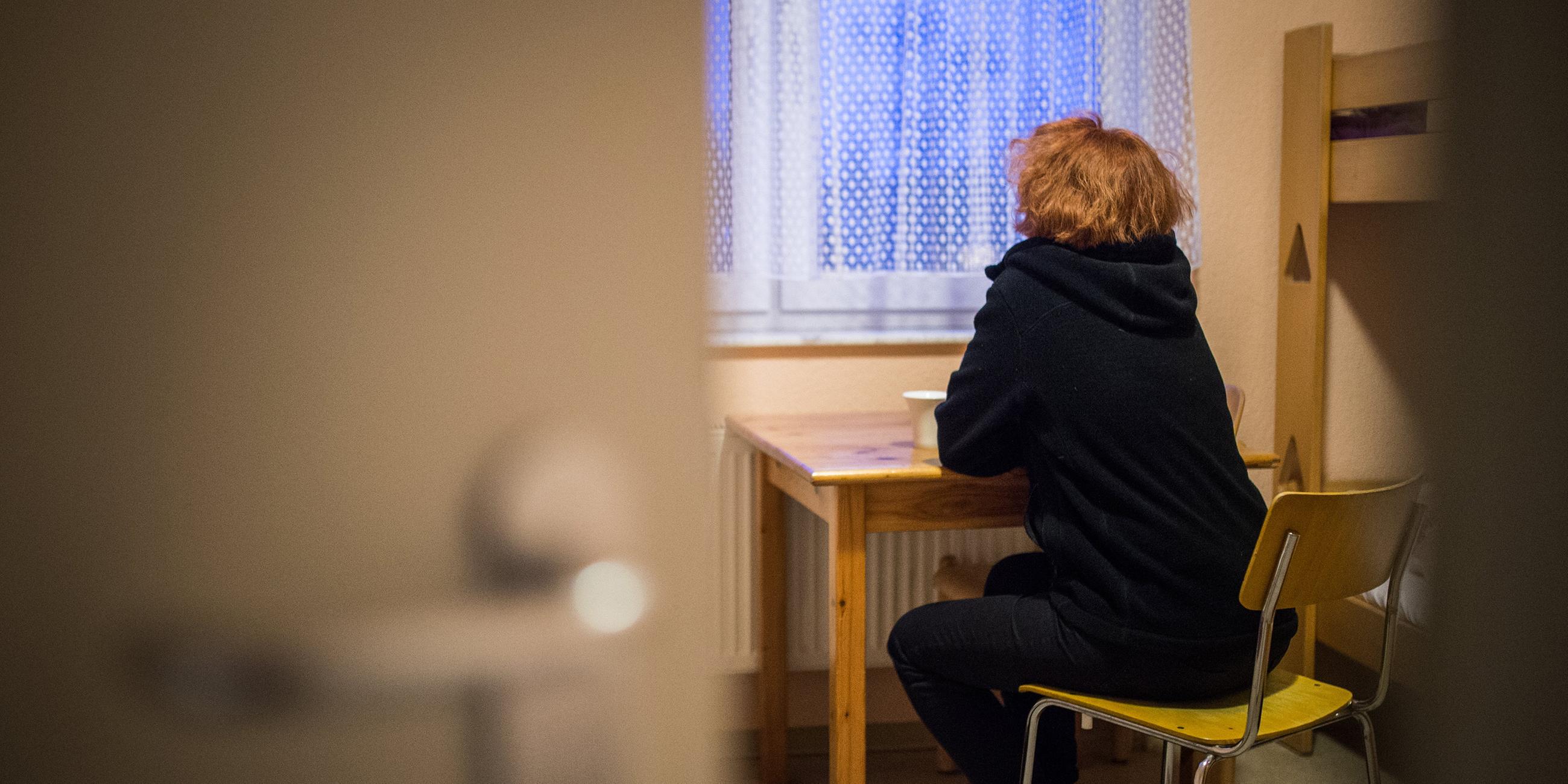 Eine Frau blickt in einem Frauenhaus aus dem Fenster