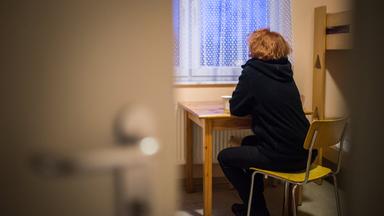 Eine Frau blickt in einem Frauenhaus aus dem Fenster