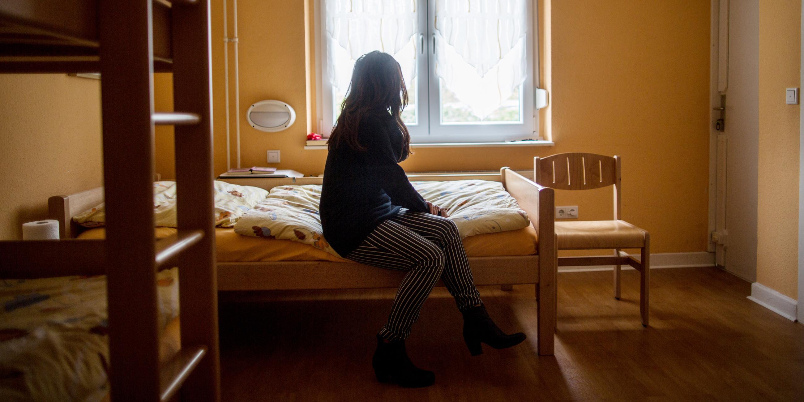 Frau sitzt auf einem Bett in einem Frauenhaus in Herne