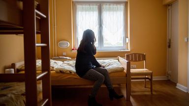 Frau sitzt auf einem Bett in einem Frauenhaus in Herne