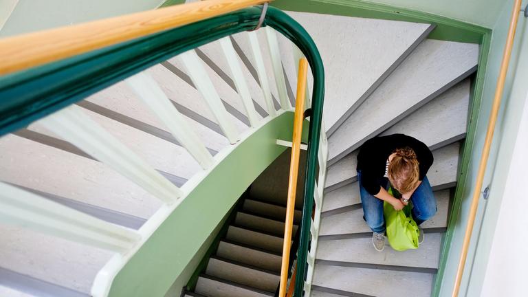 Eine junge Frau sitzt am 28.08.2013 auf einer Treppe. Frauenhäuser in Sachsen sehen sich dennoch am Limit.
