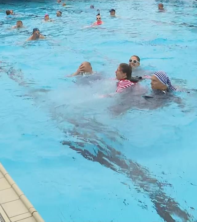 Badegäste schwimmen im Freibad.