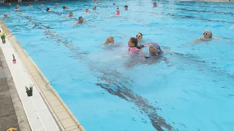 Badegäste schwimmen im Freibad.