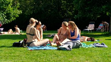 Vier Studentinnen sitzen auf einer Wiese im Freiburger "Lorettobad"