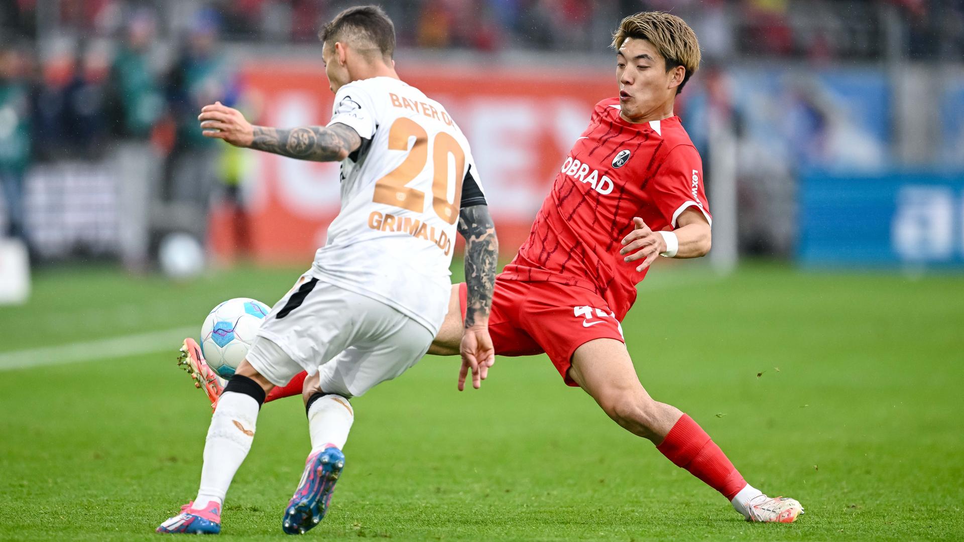 Leverkusens Alejandro Grimaldo und Freiburgs Ritsu Doan kämpfen um den Ball.