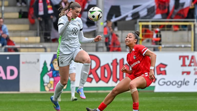 Wolfsburgs Jule Brand und Freiburgs Nicole Ojukwu im Kampf um den Ball beim Spiel am 13.04.2025.