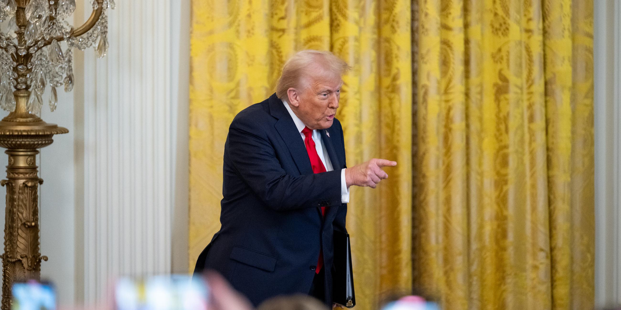 US Päsident Trump auf einer Bühne, zeigt mit erhobenen Finger in die Menge