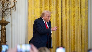 US Päsident Trump auf einer Bühne, zeigt mit erhobenen Finger in die Menge