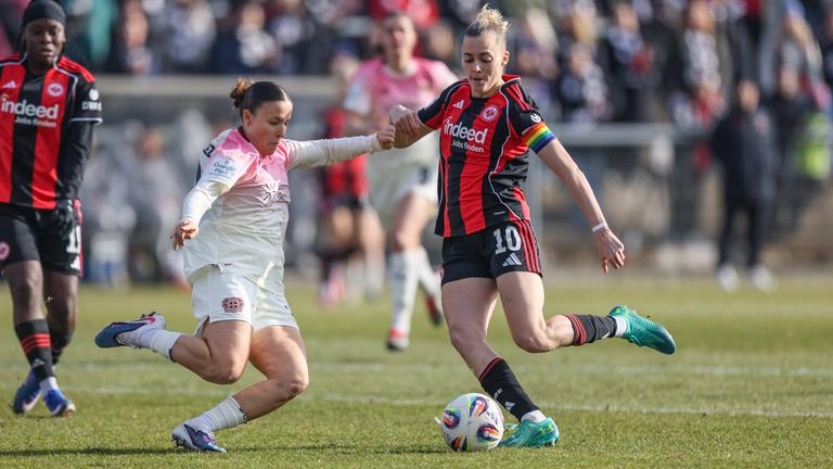 Leverkusens Außenverteidigerin Estrella Merino Gonzalez grätscht im Zweikampf mit Frankfurts Mittelfeldspielerin Laura Freigang in Richtung Ball