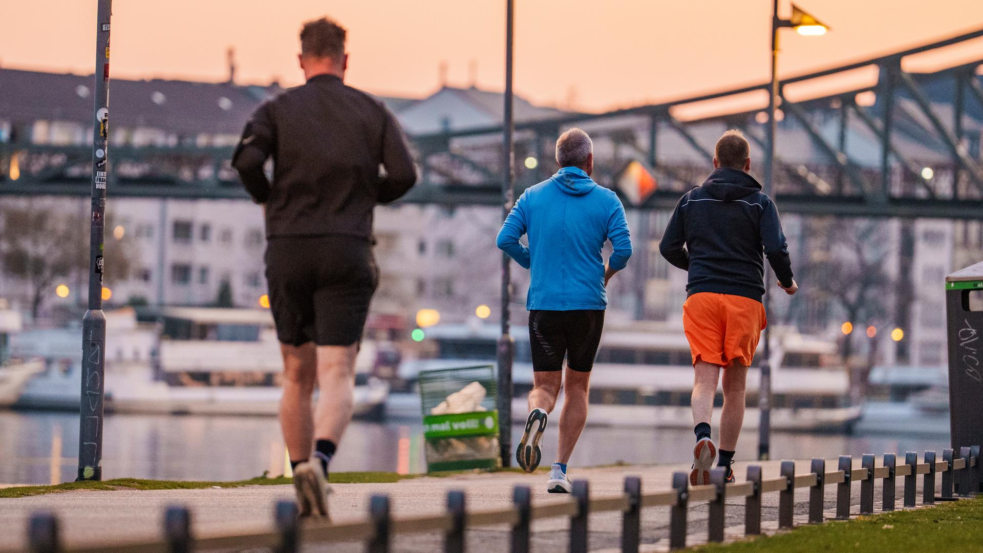 03.04.2025, Hessen, Frankfurt/Main: Jogger sind zum Sonnenaufgang am Mainufer unterwegs.
