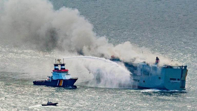 Zu sehen ist ein Boot, das versucht das Frachtschiff zu löschen. 