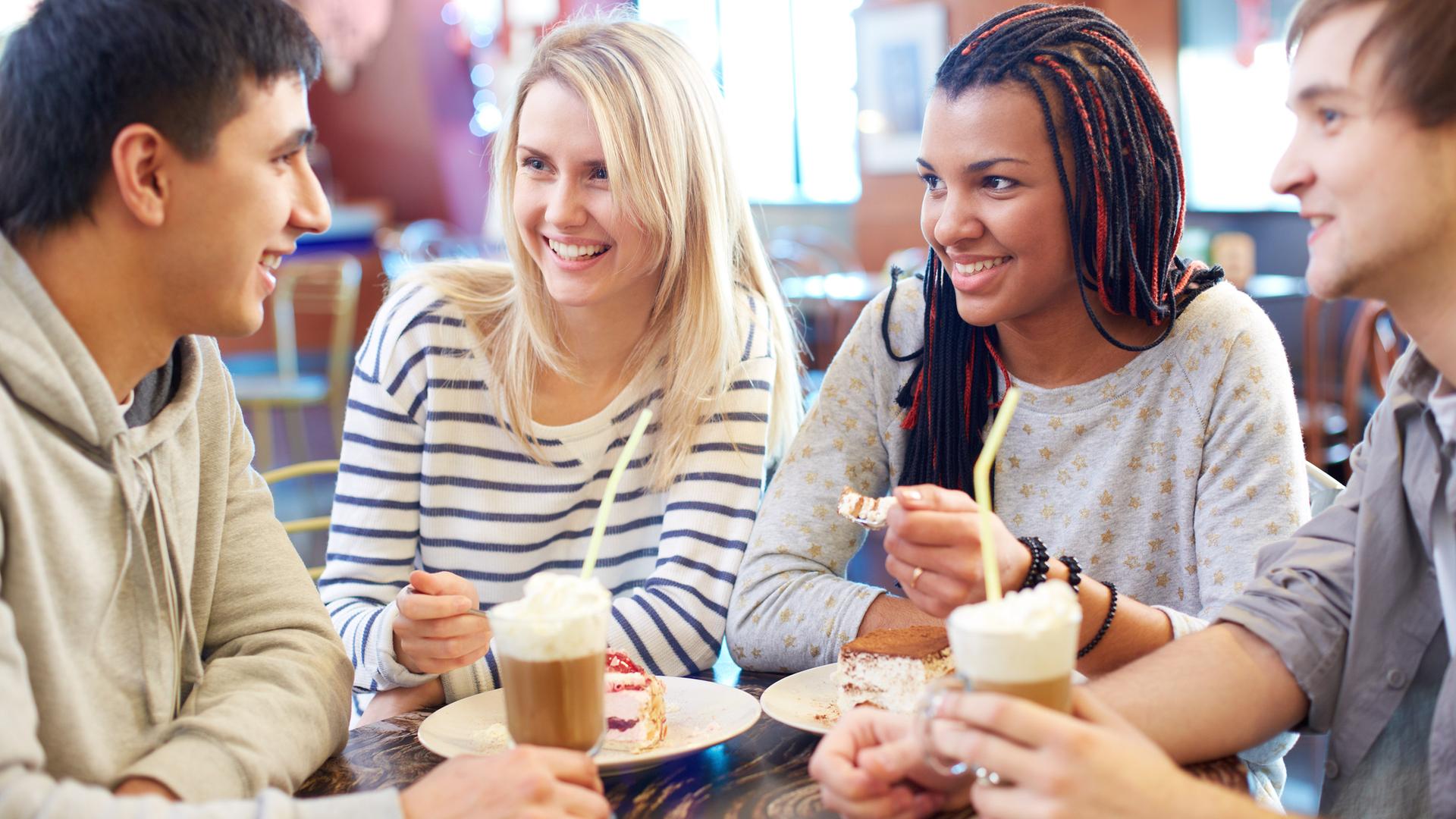 Eine Gruppe von vier Freunden sitzt zusammen in einem Café