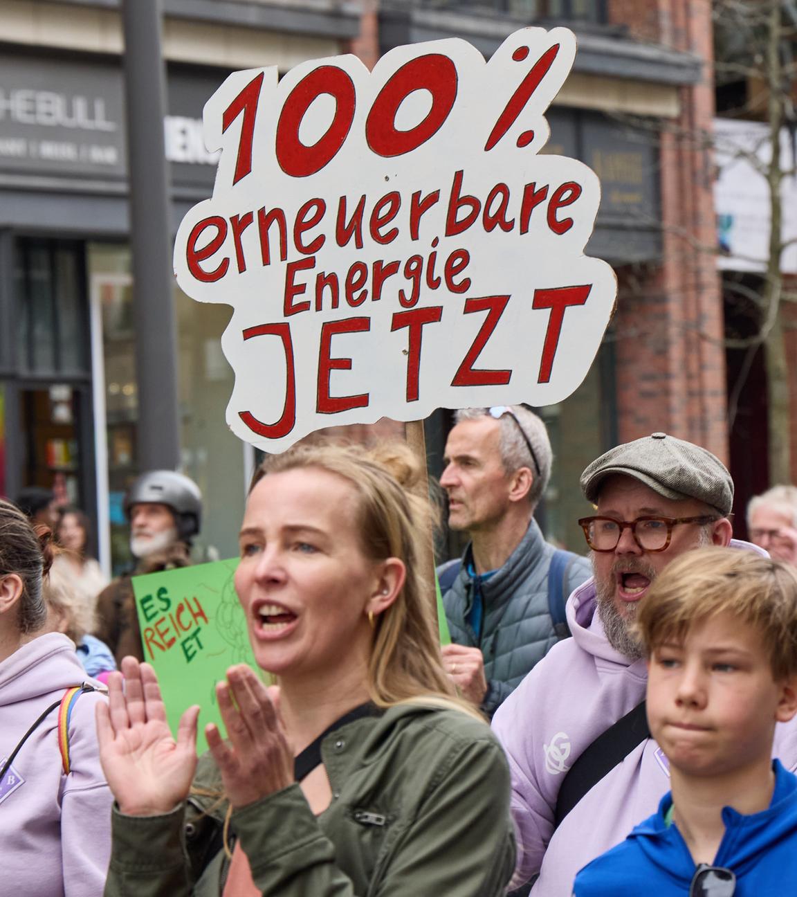 Ein Teilnehmer auf einer Demonstration für die Energiewende hält auf der Mönckebergstraße ein Transparent mit der Aufschrift "100% erneuerbare Ernergie jetzt". 