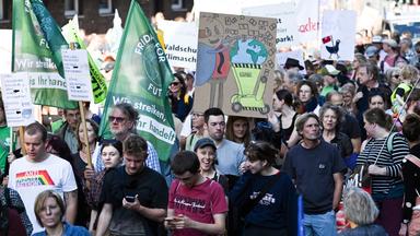 Nordrhein-Westfalen, Köln: Demonstranten ziehen mit Flaggen und Plakaten durch die Stadt.