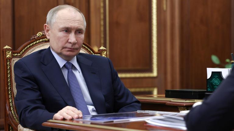 Putin sitzend und zuhörend im Anzug