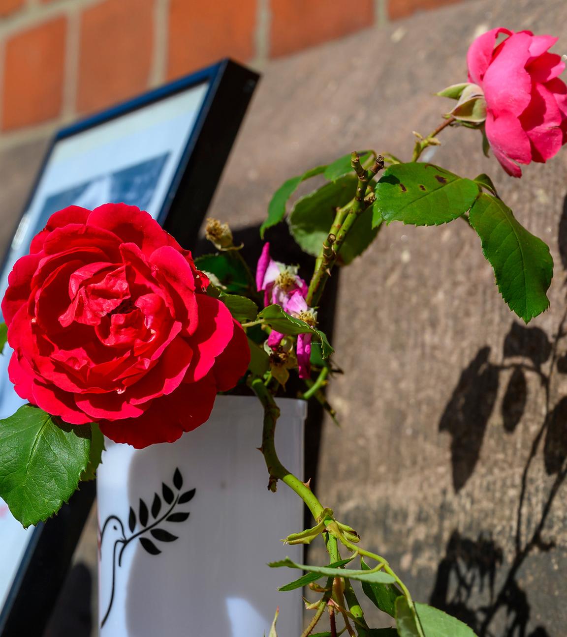 Blumen und Kerzen stehen an einem Bahngebäude.