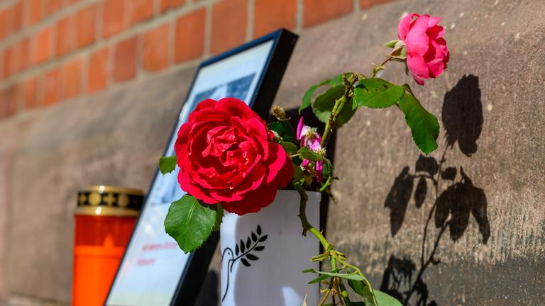 Blumen und Kerzen stehen an einem Bahngebäude.