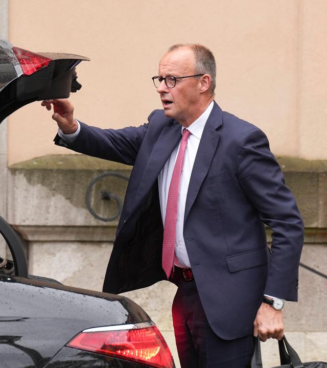 Bundeskanzler Friedrich Merz schließt den Kofferraum eines Autos. (Archivbild)