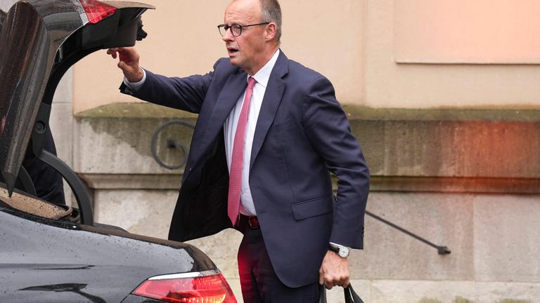 Bundeskanzler Friedrich Merz schließt den Kofferraum eines Autos. (Archivbild)