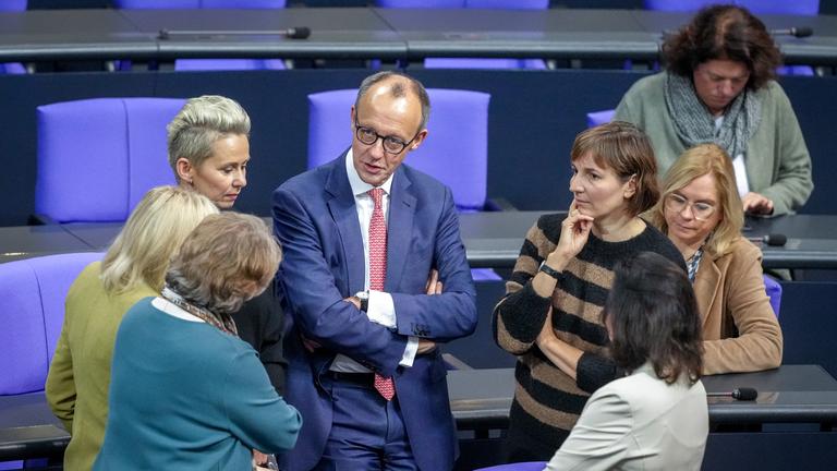 Berlin: Friedrich Merz (CDU, M), CDU-Bundesvorsitzender und Unionsfraktionsvorsitzender, steht im Plenum des Bundestags mit Abgeordneten der Unions-Fraktion zusammen.