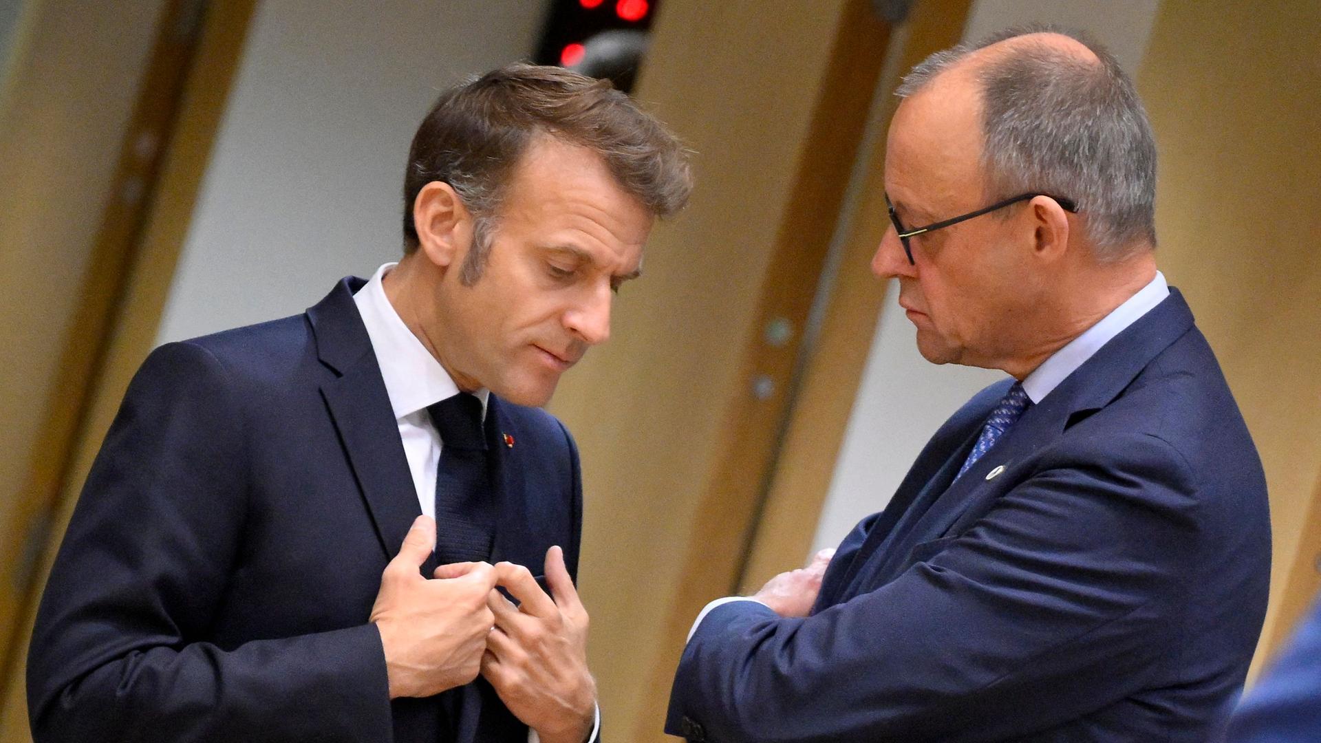 Bundeskanzler Friedrich Merz (r) spricht mit Frankreichs Präsident Emmanuel Macron bei ihrer Ankunft zu einem Treffen des Europäischen Rates in Brüssel