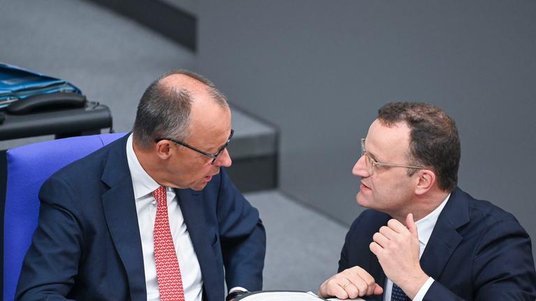 Archiv:  Bundeskanzler Friedrich Merz (l,CDU) unterhält sich mit Jens Spahn, Vorsitzender der Unions-Fraktion im Bundestag, während der Generaldebatte zum Haushalt im Plenum des Bundestags. 