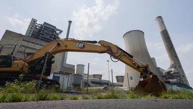 Ein Bagger ist vor dem RWE Braunkohlekraftwerk Frimmersdorf mit seinen Kühltürmen zu sehen. 