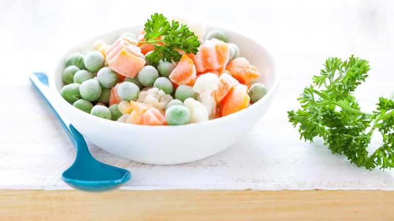 Tiefkühlgemüse in einer Schüssel mit einem Löffel daneben