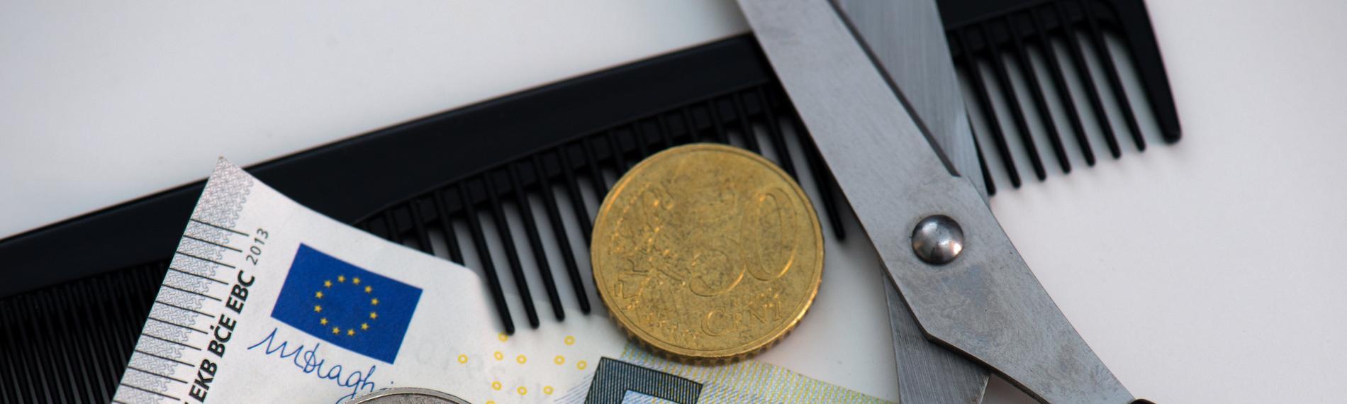 8,50 Euro liegen auf einem Tisch mit Kamm und Schere