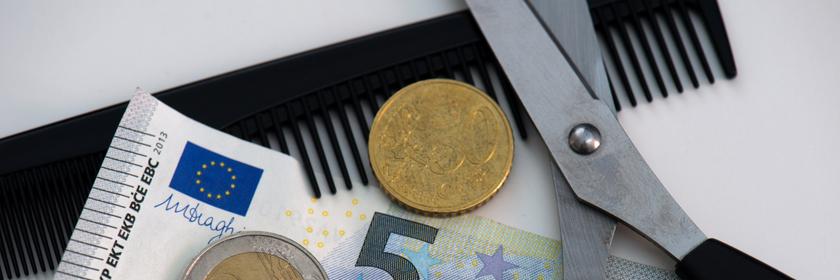 8,50 Euro liegen auf einem Tisch mit Kamm und Schere