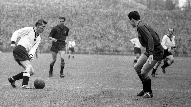 Fritz Walter führt den Ball zwischen zwei Gegenspielern.