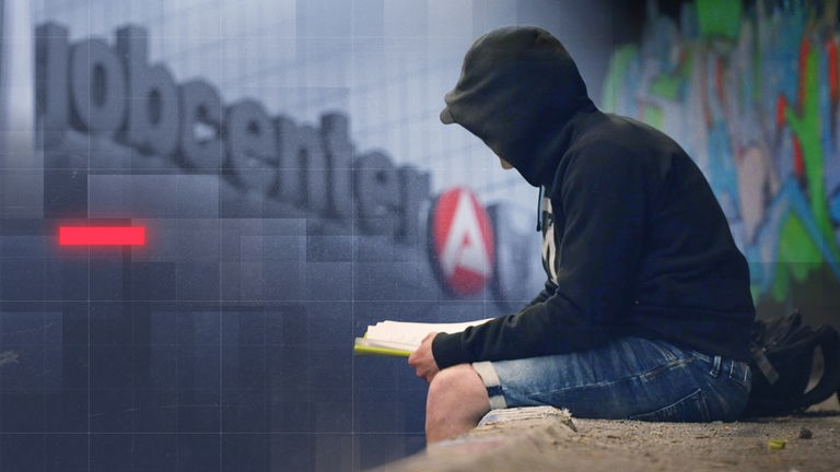 Mann mit schwarzem Hoodie sitzt vor einem Gebäude mit "jobcenter"-Schriftzug