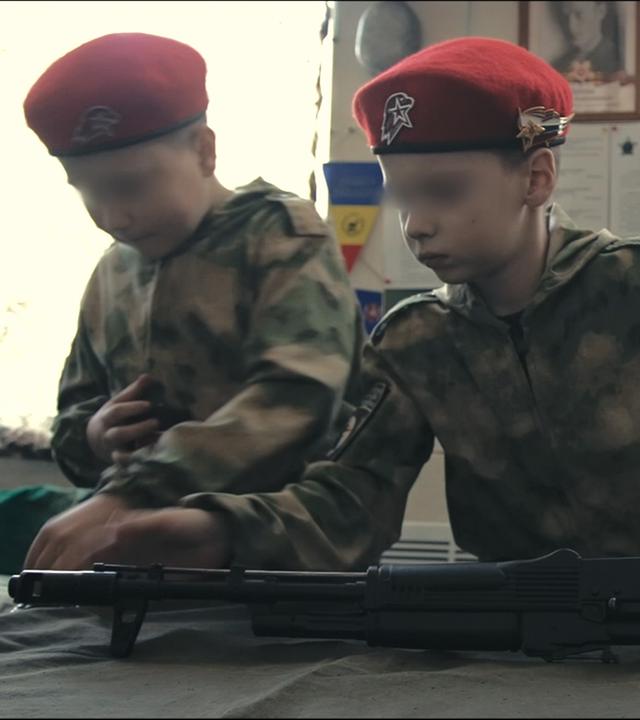 Montage: Kinder werden an Waffen ausgebildet