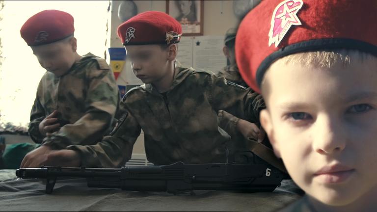 Montage: Kinder werden an Waffen ausgebildet