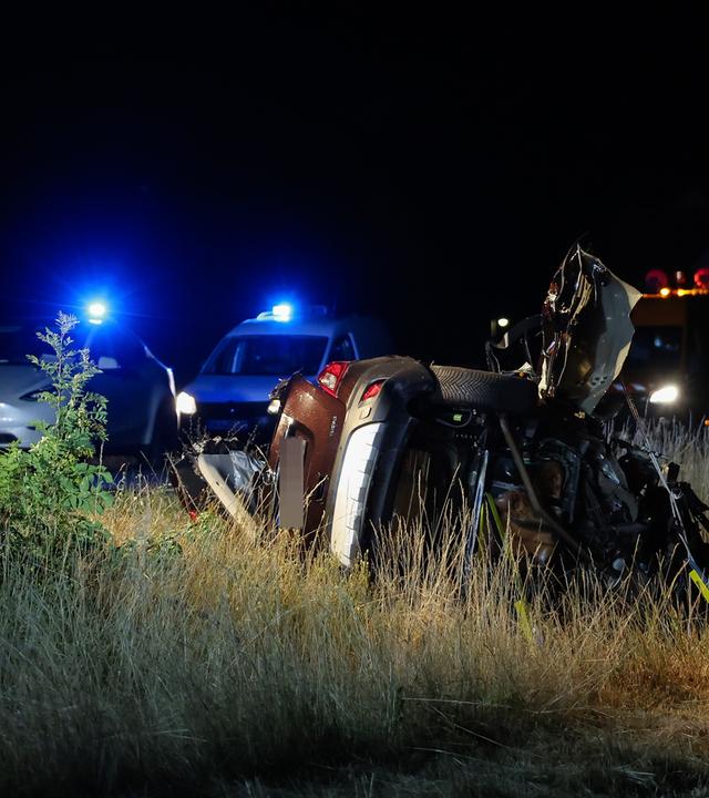 Ein vom Unfall beschädigtes Auto und zwei Polizeiwagen. 