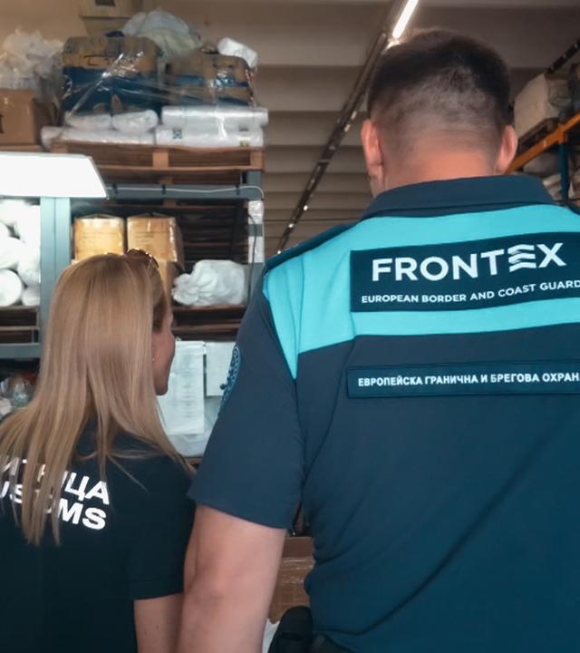 Grenzbeamte und ein Frontex-Mitarbeiter im Lager mit beschlagnahmten Waren
