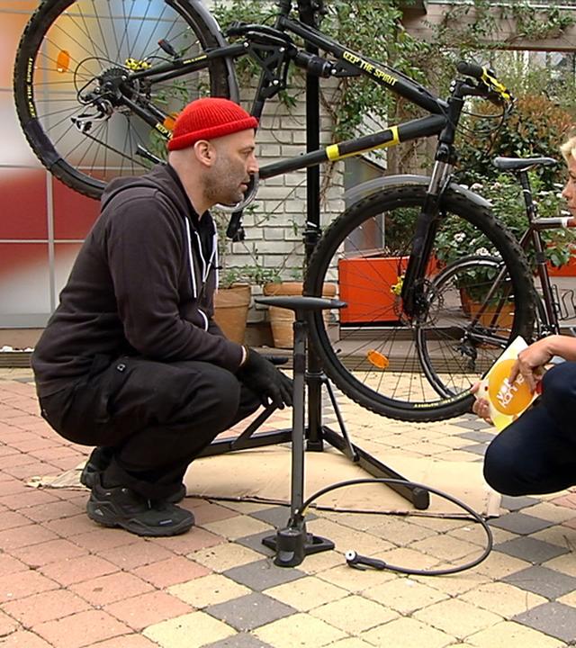 Uwe-Jens Spielmann und Nadine Krüger hocken vor einem Fahrrad.