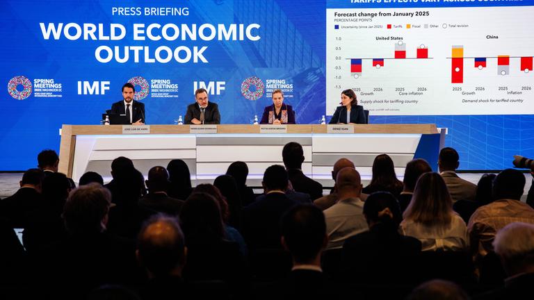 Frühjahrstagung des IWF und der Weltbank. Vier Menschen sitzen an einem Pult vor einer blauen Wand.