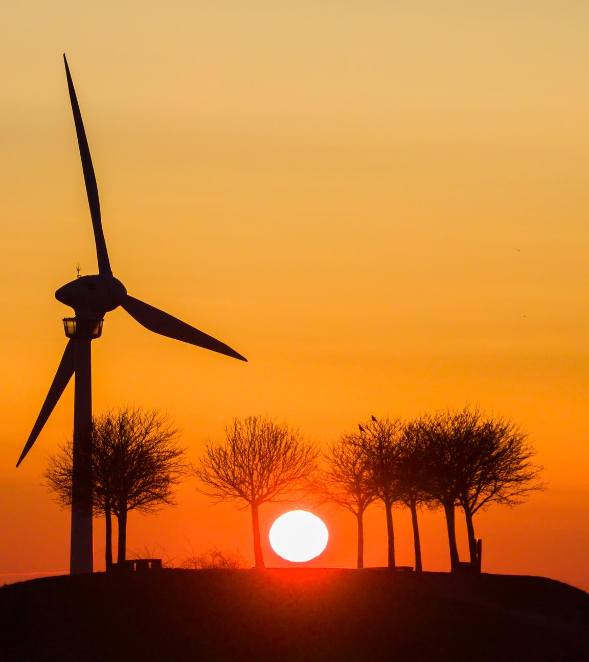 06.03.2026, Niedersachsen, Hannover: Die Sonne geht am Kronsberg hinter einem Windrad auf.
