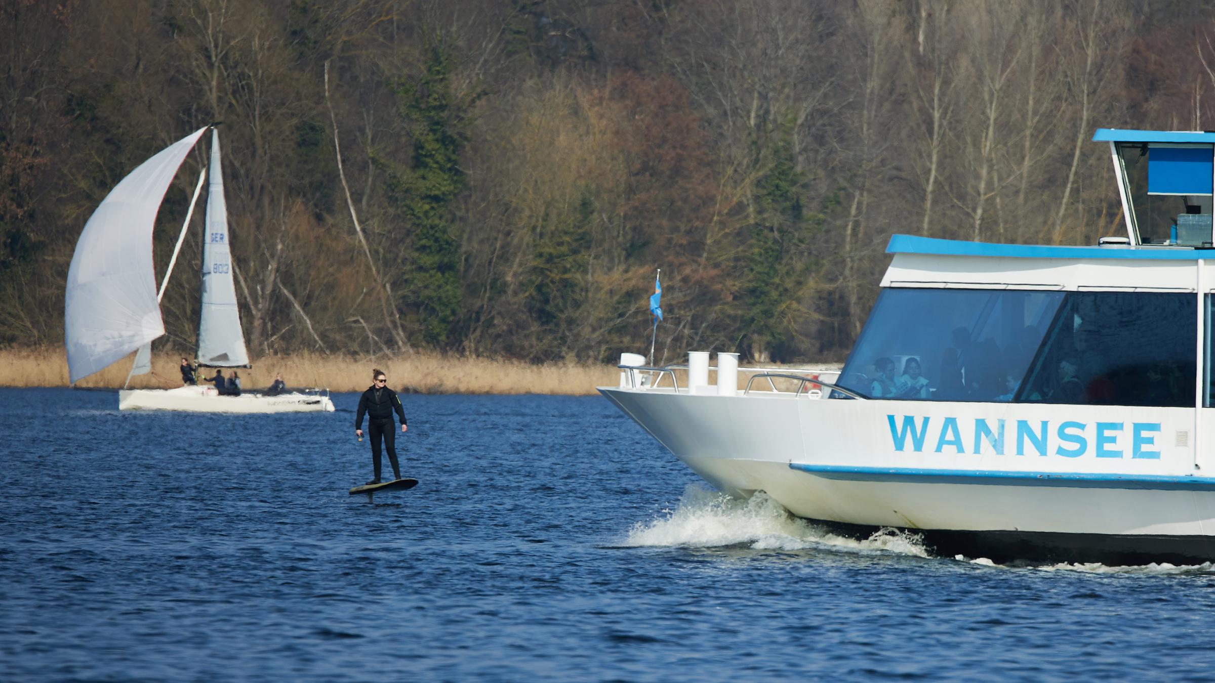 Berlin: Bei milden Temperaturen begegnet ein Fahrer auf einem eFoil einer Fähre auf dem Großen Wannsee.
