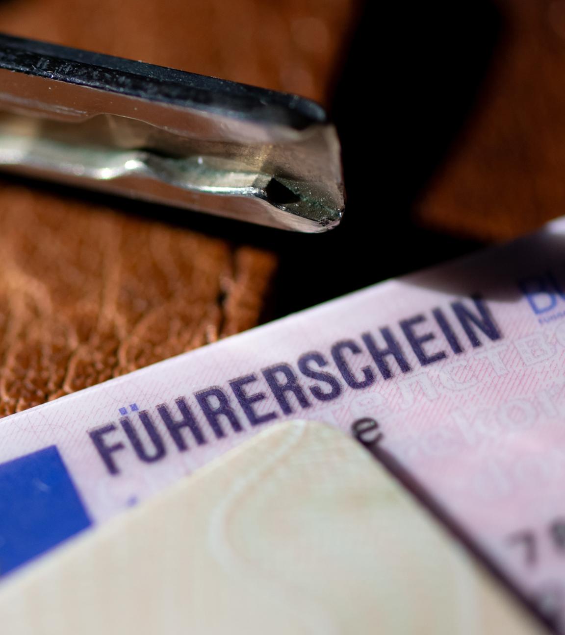 Ein Führerschein, ein Autoschlüssel und ein Personalausweis liegen auf einem Portemonnaie.