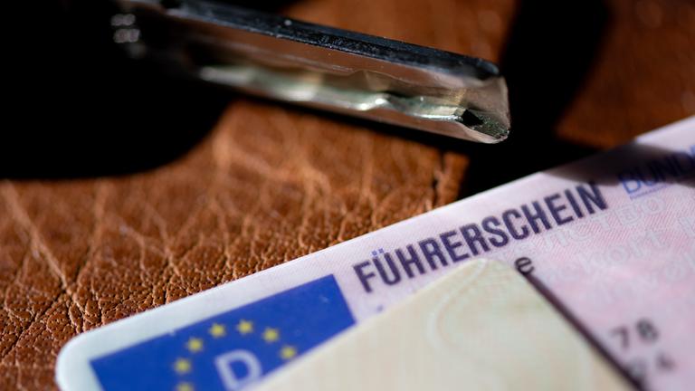 Ein Führerschein, ein Autoschlüssel und ein Personalausweis liegen auf einem Portemonnaie.