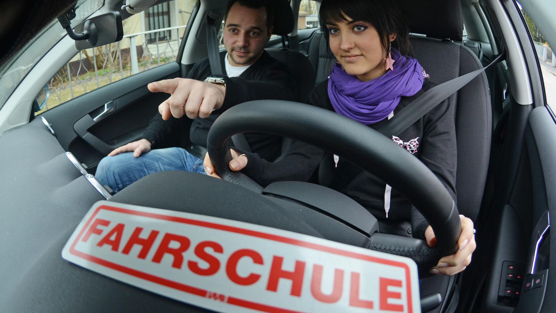 Fahrschülerin und Fahrlehrer sitzen in einem Fahrschulauto
