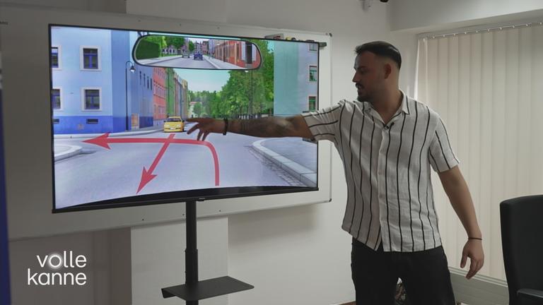 Ein Fahrlehrer erklärt im Theorie-Unterricht am Bildschirm eine Verkehrssituation.