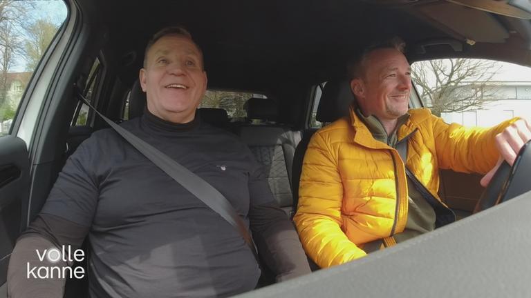 ZDF-Reporter Henning Behrens sitzt mit Fahrschullehrer im Auto